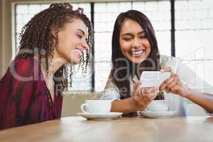 Female friends having coffee and looking at a smartphone