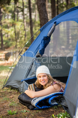 Pretty blonde camper smiling and lying in tent