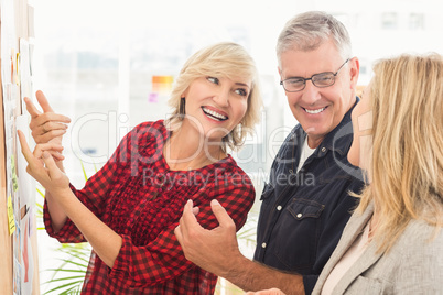 Smiling business team looking at notes on the wall