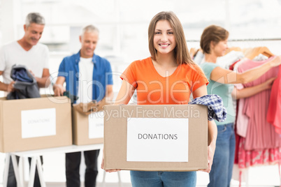 Smiling casual businesswoman holding donation box