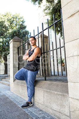 Portrait of a handsome athlete leaning against a fence