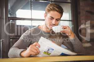 Handsome man drinking coffee and reading newspaper