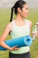 Sporty woman holding exercise mat and water bottle