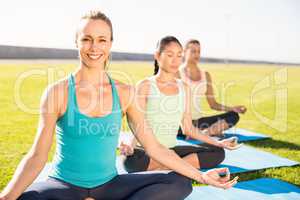 Smiling sporty blonde doing yoga with her friends