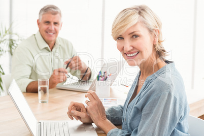 Smiling business team working on laptops