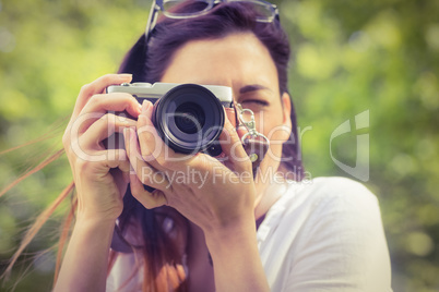 Beautiful brunette taking photo in the park