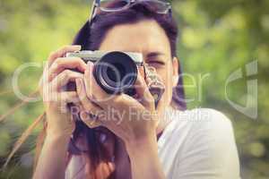 Beautiful brunette taking photo in the park