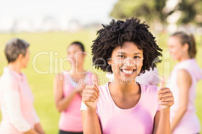 Smiling young woman wearing pink for breast cancer in front of f