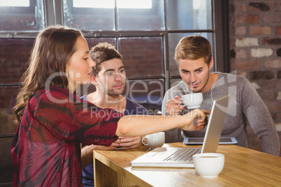 Friends having coffee and using laptop together