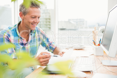 Smiling casual designer working at his desk