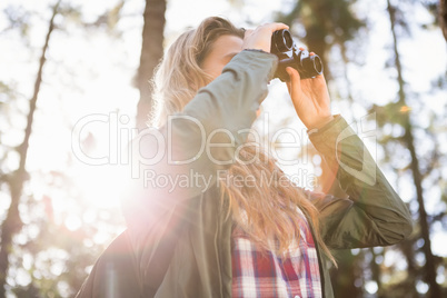 Blonde hiker looking through binoculars