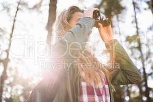 Blonde hiker looking through binoculars