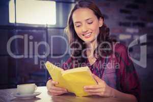Smiling brunette reading yellow book