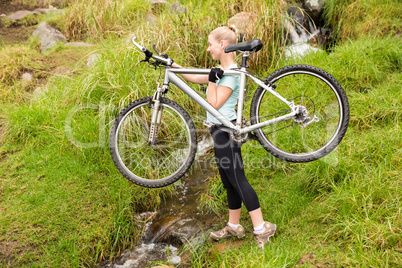 Smiling fit woman lifting her bike