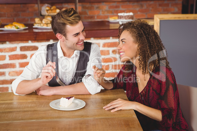 Young happy couple feeding each other with cake