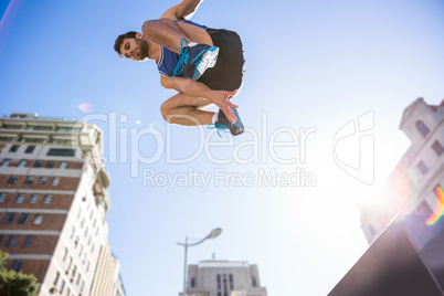 Handsome athlete jumping off the column