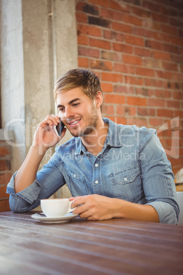 Handsome man having coffee and phoning