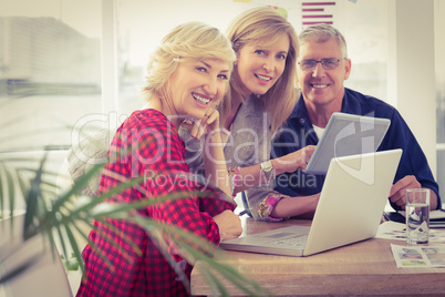 Smiling business team working on tablet and laptop