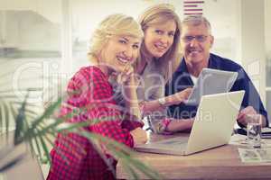 Smiling business team working on tablet and laptop