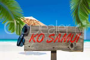 Holzschild mit der Aufschrift "Ko Samui" unter Palmen am Sandstr