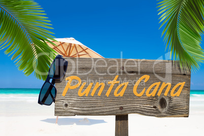 Holzschild mit der Aufschrift "Punta Cana" unter Palmen am Sands