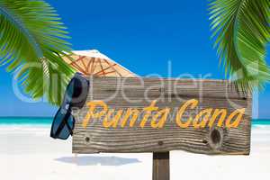 Holzschild mit der Aufschrift "Punta Cana" unter Palmen am Sands
