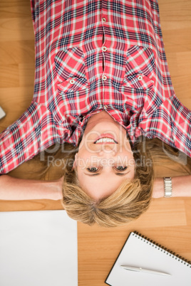 Smiling woman lying on floor surrounded by office items