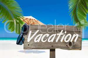 Holzschild mit der Aufschrift "Vacation" unter Palmen am Sandstr