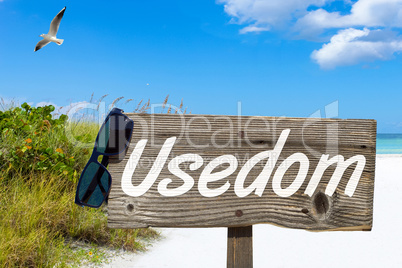 Holzschild mit der Aufschrift "Usedom" am Sandstrand