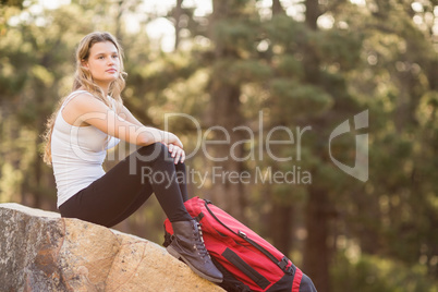 Young jogger sitting on rock and looking away