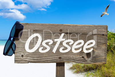 Holzschild mit der Aufschrift "Ostsee" am Sandstrand
