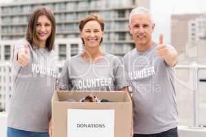 Smiling volunteers with donation box doing thumbs up