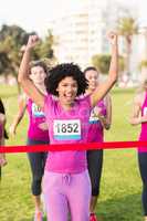 Cheering young woman winning breast cancer marathon