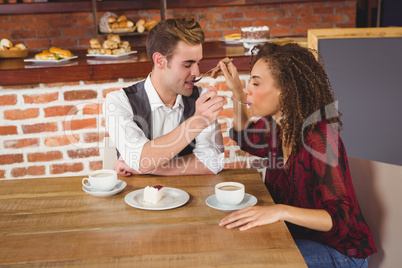 Young happy couple feeding each other with cake