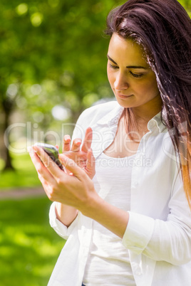 Beautiful brunette in the park sending text