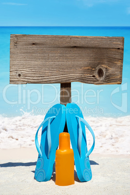 Flips Flops stehen vor leerem Holzschild am Strand