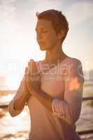 Peaceful sporty woman meditating at promenade