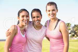 Three smiling women wearing pink for breast cancer