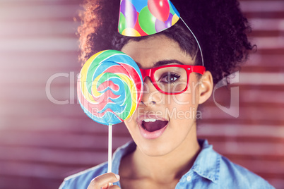 Surprised young woman holding a lollipop against her face