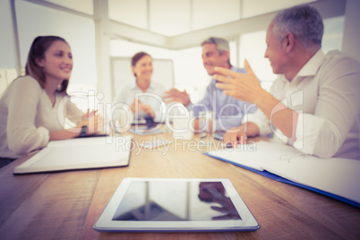 Tablet in front of talking business people