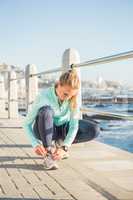 Fit blonde tying her shoelace and listening to music