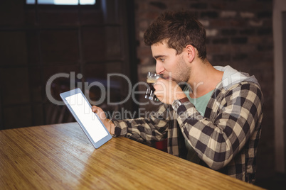 Hipster drinking coffee and looking at tablet computer