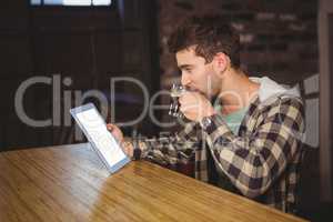 Hipster drinking coffee and looking at tablet computer