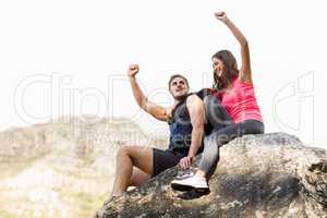 Young happy joggers sitting on rock cheering