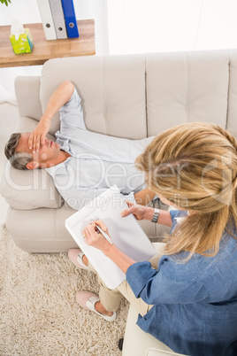 Depressed man lying on couch and talking to therapist