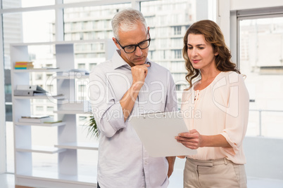 Casual business colleagues looking at clipboard