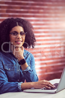 Casual businesswoman using laptop and smartwatch