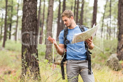 Young handsome hiker using map and compass