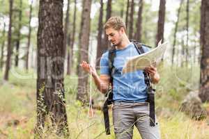 Young handsome hiker using map and compass