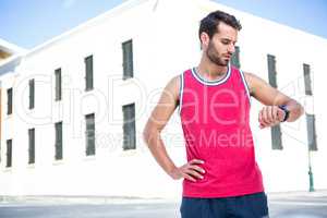 Handsome athlete checking time with hands on hips